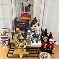 Full display showing all items in the lot including night lights, elves, mugs, plates, village church, stocking holders, and candle holder.