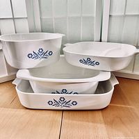Four vintage Corning Ware Blue Cornflower baking dishes stacked showing exterior patterns and shapes.