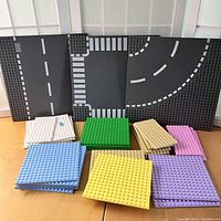 Full view of all LEGO base plates arranged on a table showing roads and colored plates.