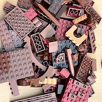 Top view showing a pile of assorted LEGO bricks in shades of brown including large plates, curved bricks, and small blocks.