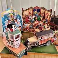 Photo showing four Christmas 3D pop-up cards from different angles: boat, vintage car with Santa, peace on earth angel, and Santa with elves scenes.
