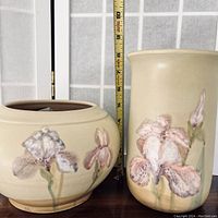 Full view of both pottery pieces showing their size against a measuring tape and the floral motifs