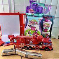 Lot overview including Blume toy set, Osmo creative board, vintage metal train, wood fire truck, and Little Live Pets.
