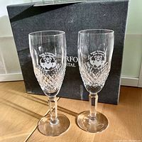 Two Waterford anniversary champagne flutes standing in front of original box.