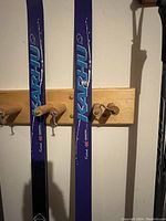 Blue Karhu cross country skis hung on wall hooks, showing brand name and design.