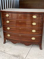 Full front view of the wooden dresser with curved front, showing four drawers with brass handles.