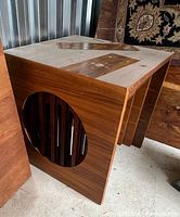 Top and side angle showing wood grain, tabletop and circular cutout detail on side panel of nesting table