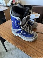 Side and angled view of a blue and gray snowboard boot showing exterior details and condition.