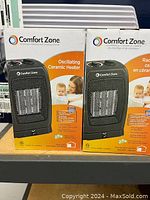 Two boxed Comfort Zone oscillating ceramic heaters, black color, new in box, labeled in English and French.