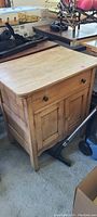 Wooden cabinet table showing overall front and side view, weathered condition with round knobs on drawer and doors.