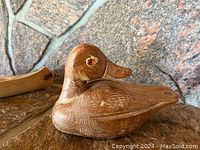 Close-up of hand-carved wooden duck figurine showing wood grain and details of the bird