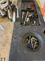 Close-up of black work bench with compartments holding screws, bolts, and small hardware.