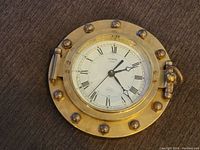Clock face view showing brass with rivet details and Roman numerals.