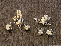 Two brooches and two pairs of clip-on earrings arranged on dark fabric