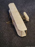 Top angle view showing the entire model airplane with fabric-covered wings and tail, wooden frame, and rigging wires visible.