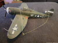 Side view of the military model airplane on a gray surface showing the VF-T markings and star insignia on the wing.