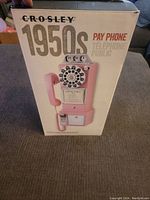 Box showing the Crosley 1950s pink pay phone replica image and branding.