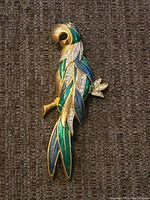 Front view showing detailed parrot brooch with green and blue enamel and clear stones.