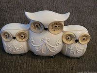 Front view of the mid century triple owl ceramic figurine on gray fabric surface.