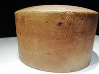 Photo showing the side profile of the wooden hat mold block, highlighting the oval shape and wood grain texture