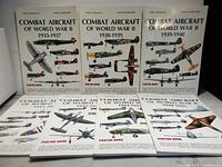 Eight hardcover 'Combat Aircraft of World War II' poster books by Enzo Angelucci and Paolo Matricardi displayed upright and laid flat, showing covers with WWII aircraft illustrations and time periods from 1933-1945.