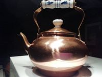Photo showing entire copper kettle with rounded body and blue and white ceramic handle and lid knob.