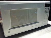 Full front view of white GE microwave oven with viewing window and turntable inside.
