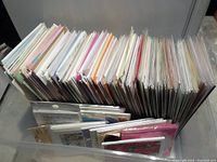 Top view of over 200 greeting cards and notecards in original packaging, arranged upright and tightly packed.