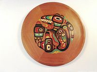 Full overhead view of handcrafted circular cedar wood tray with intricate raven and whale painting