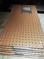 Stack of twelve shrink-wrapped pegboard sheets showing front faces