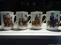 Front view of all four Norman Rockwell mugs showing distinct illustrated scenes on each.