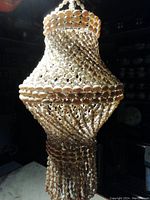 Full view of the hanging decorative piece showing its intricate seashell arrangement and tiered shape, showcasing its size and style.
