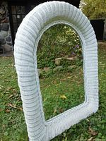 Full view of the white wicker framed mirror showing its arch shape and woven wicker texture.