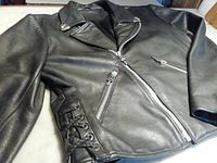 Angled front view of jacket showing diagonal zipper closure, lapel collar and side lace-up detail.