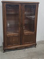 Front view of solid wooden antique curio cabinet with closed glass doors.