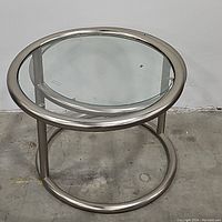 Front view of two-tier round chrome side table showing chrome frame and glass surfaces