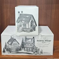 Photo of 2 box sets showing the Dickens Village Series 'Start a Tradition' set containing 13 pieces of Christmas village houses and figures by Department 56.