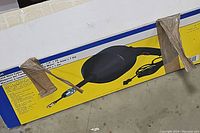 Boxed bench grinder with black and yellow packaging and power cord visible, taped for shipping