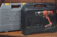 Ryobi and Black & Decker tool cases side by side on shelf, Ryobi case gray with yellow latches, Black & Decker case black with red drill pictured on front.
