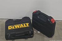Two hard plastic carrying cases on the floor, one labeled DEWALT, the other unlabeled with red clasps.