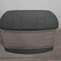 Front view of Rubbermaid outdoor storage bin showing the beige body and black lid closed.