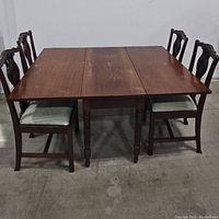 View of dining table with four chairs placed around it, showing table surface and chair details.