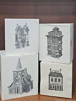 Four original boxed village house models with black-and-white box illustrations, showing different house styles and details.