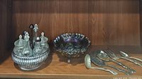 Photo of antique spinning cruet set, vintage carnival glass fruit bowl, and vintage serving utensils on wooden shelf