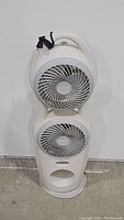 Full view of white Holmes pedestal fan with two fans stacked vertically and carrying handle