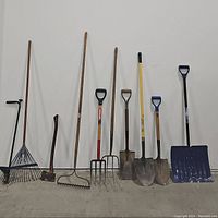Full view of all yard tools including 4 shovels, 2 garden forks, 2 rakes, and 1 axe arranged against a white wall.