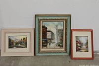 Three framed art prints displayed side by side: autumn landscape, city street scene, garden pathway