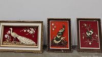 Three framed bird art pieces showing white peacock, green and white peacock, and love birds on a red background.