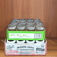 Photo of one box of 12 Ball mason jars for preserving, regular mouth pint size (16 oz), with metal lids and bands, in used condition.