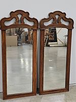 Two 20 x 51 inch carved wood framed mirrors standing side by side, showing full length and carved tops.